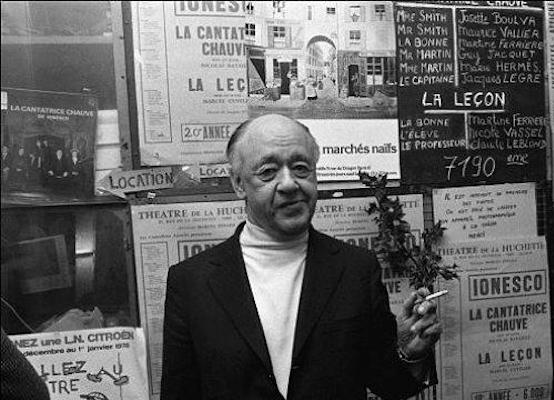Eugene Ionesco in front of a billboard displaying his works