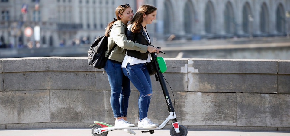 Two girls sharing a scooter ride