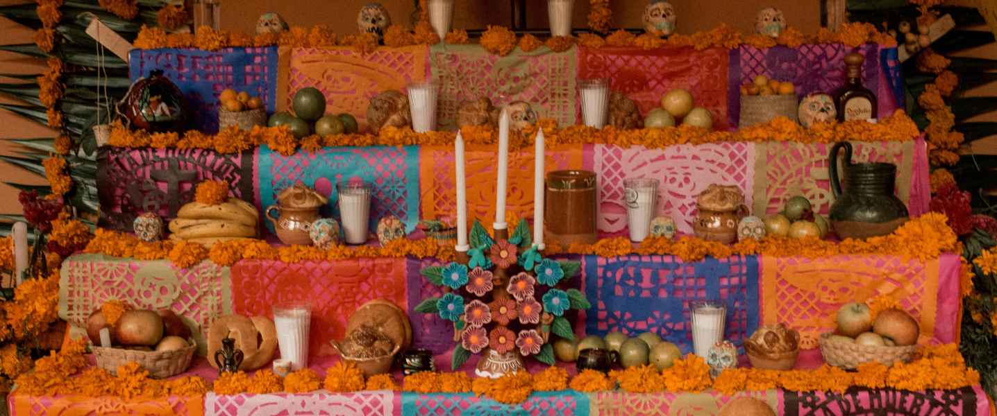Altar (ofrendas) covered in marigolds, candles and sugar skulls